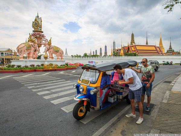 Tuk tuk and driver with two passengers on a Bangkok street